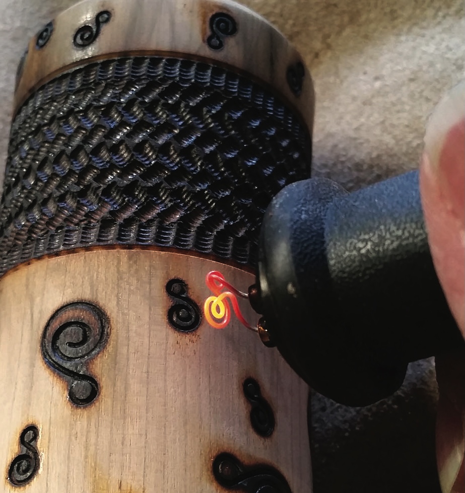 Woodburning spiral design on wooden object.