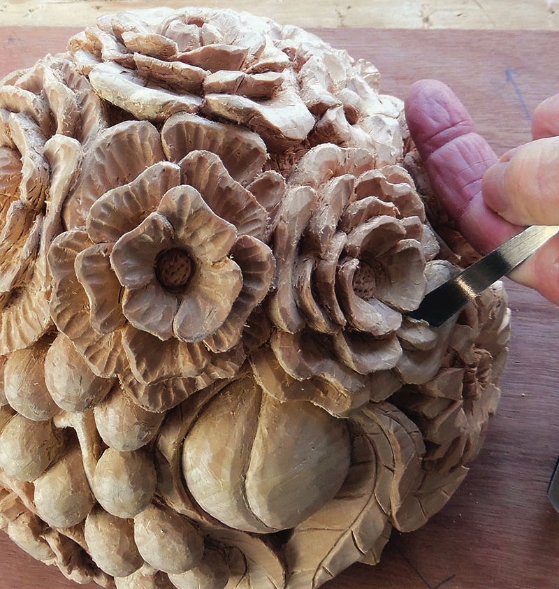 Hand carving intricate floral wood design.