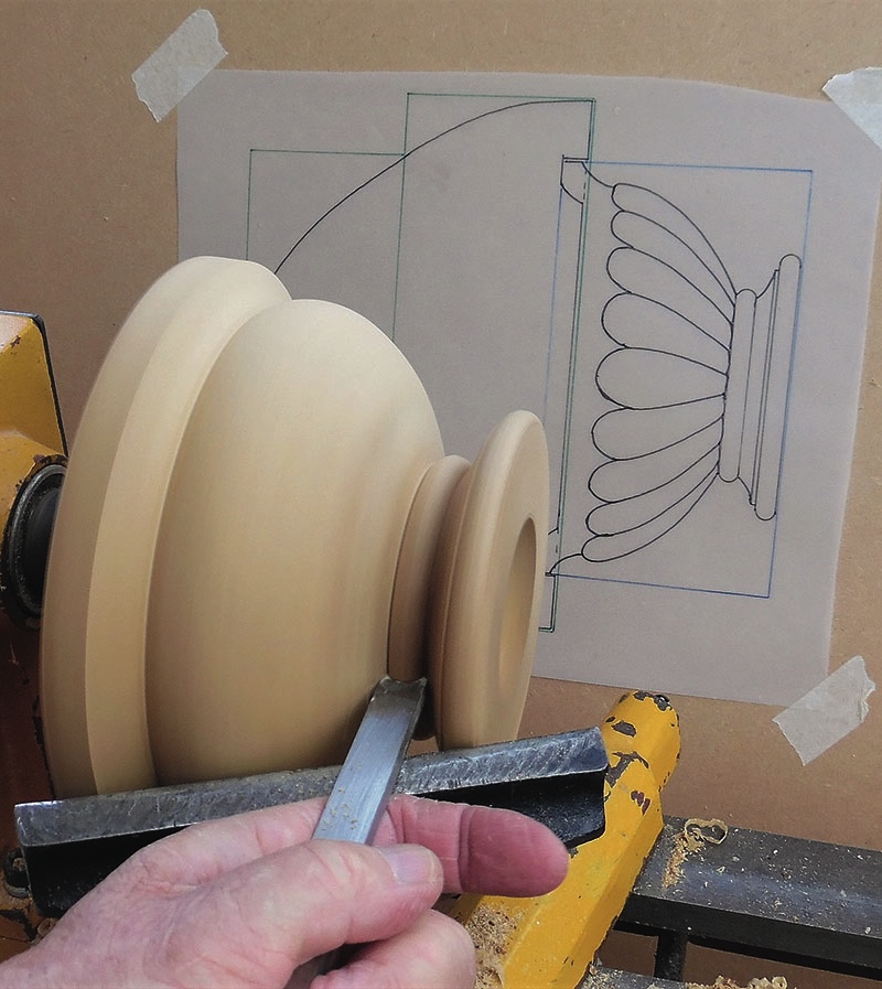 Woodturning a wooden piece with detailed design sketch.