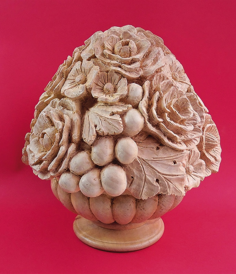 Ornate stone floral sculpture on red background.