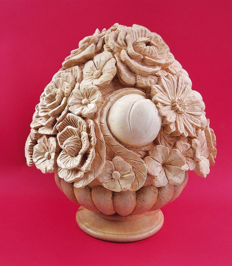 Wooden floral sculpture on pink background.