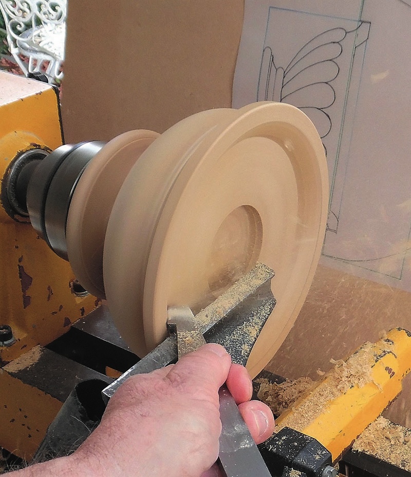 Woodturning on lathe with hand-held tool.