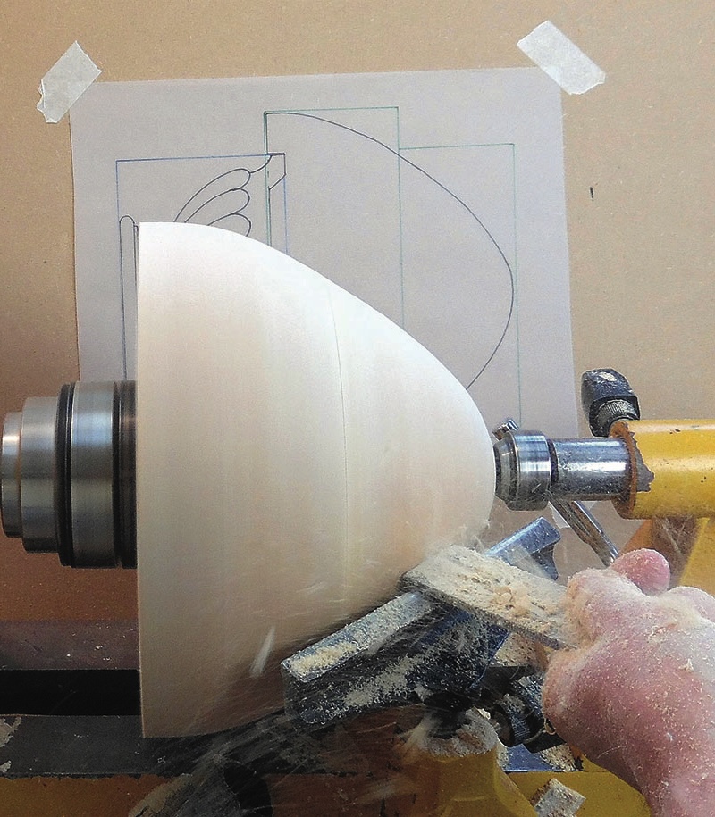 Woodturning on a lathe with hand shaping tool.