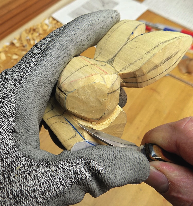 Hand-carving wooden rabbit sculpture with craft knife.