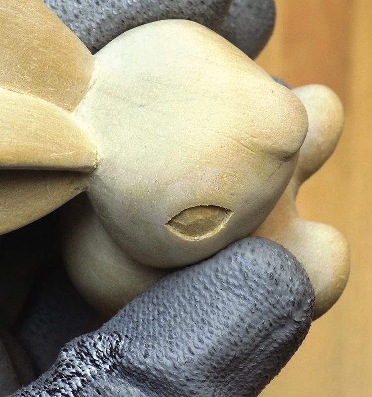 Carved wooden rabbit in gloved hand