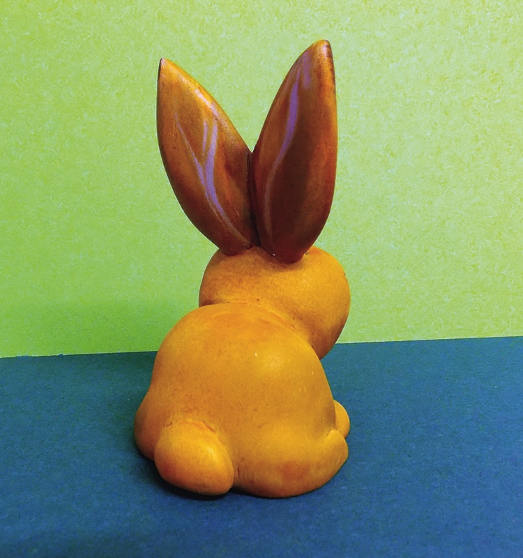 Ceramic rabbit figurine on two-tone background.