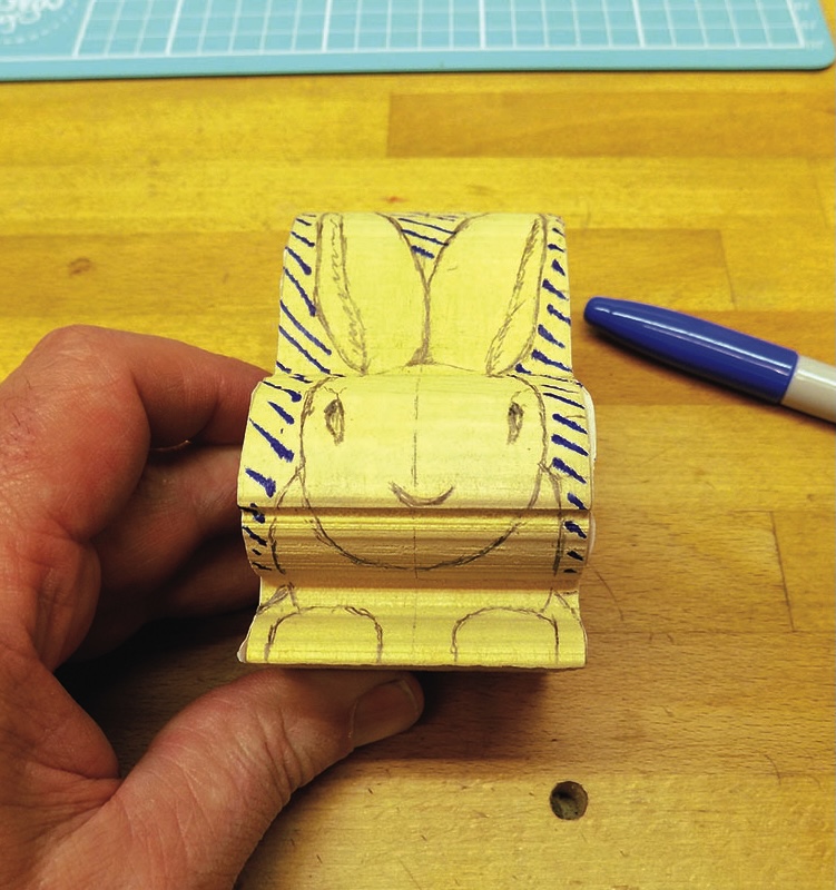 Wooden block with rabbit drawing, held by hand.