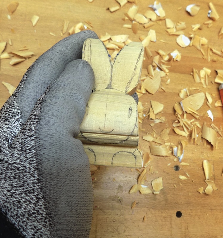 Gloved hand carving wooden rabbit figurine