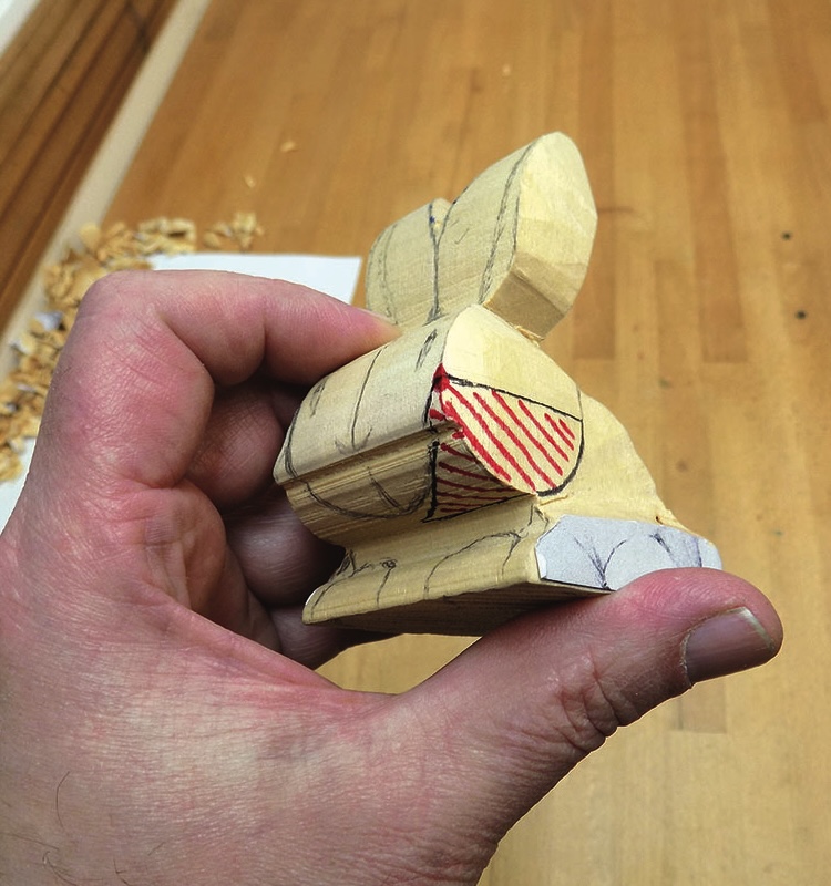 Hand holding a partially carved wooden bunny.