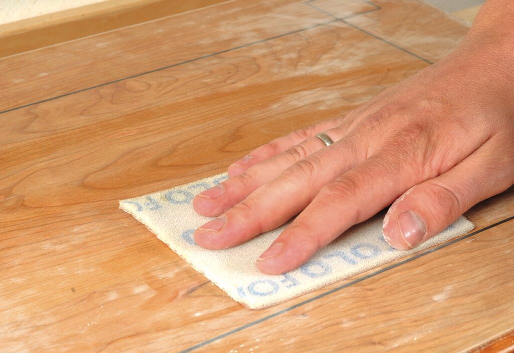 Hand sanding wooden floor with sandpaper