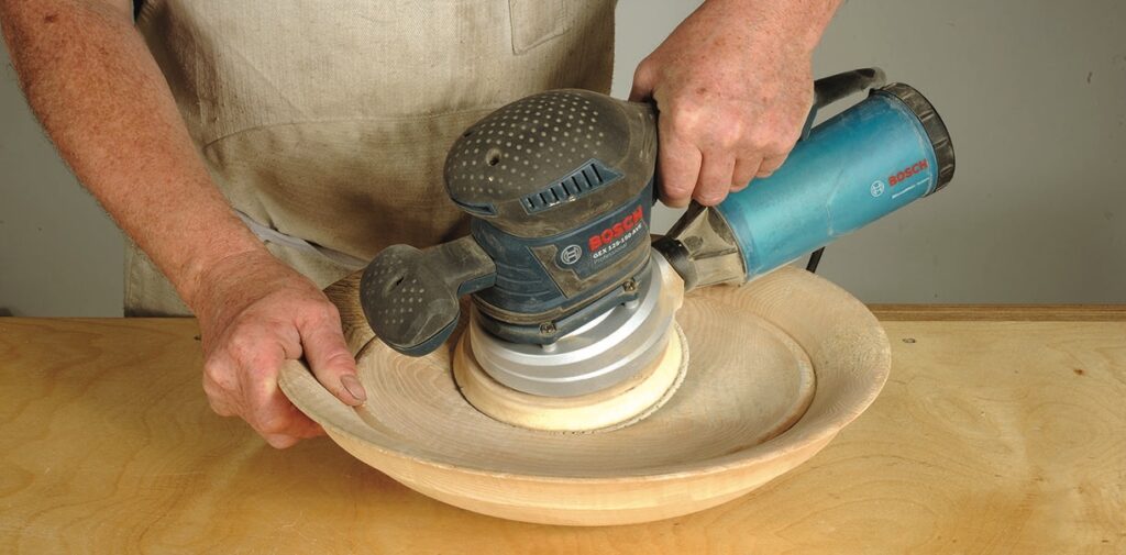 Sanding wood bowl with electric sander.
