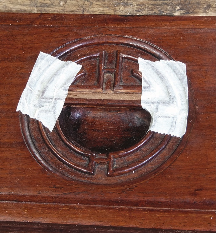 Wooden furniture handle with masking tape.