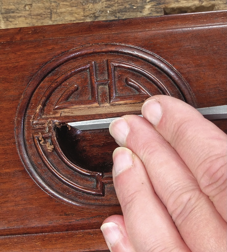 Hand carving intricate design on wooden surface.