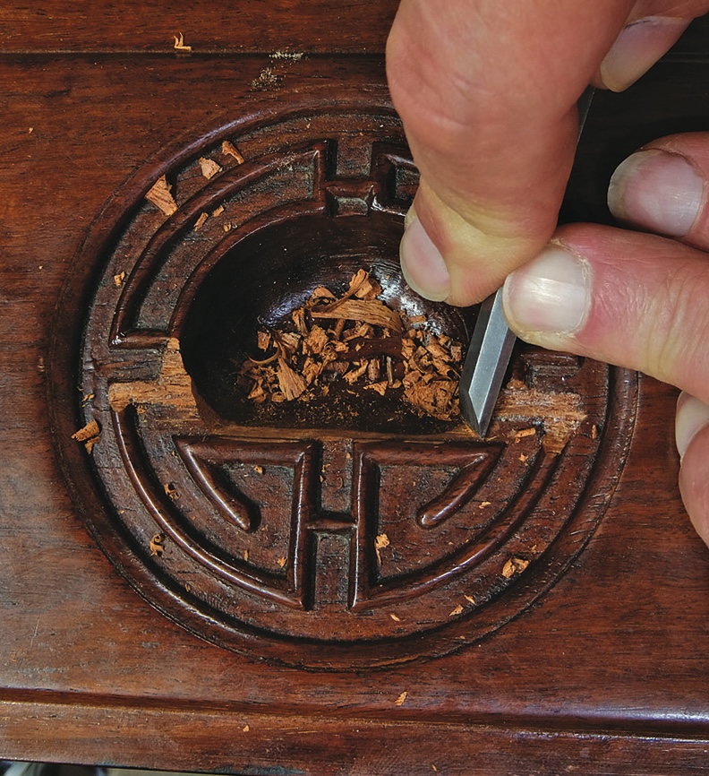 Carving wood with chisel and hand detail.