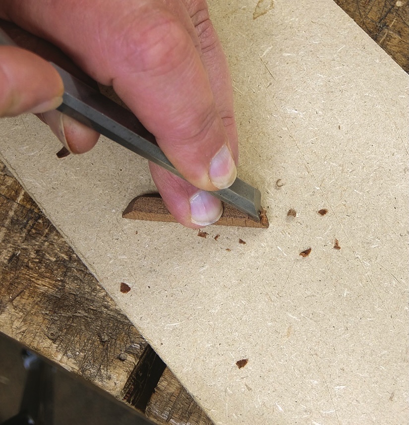 Hand carving wood with chisel and block.