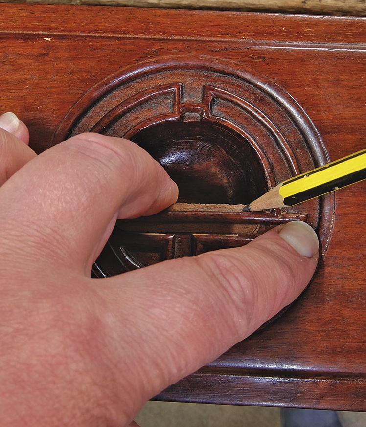 Tracing wooden detail with pencil on furniture.