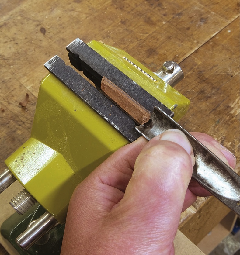 Carving wood with chisel in table vise.