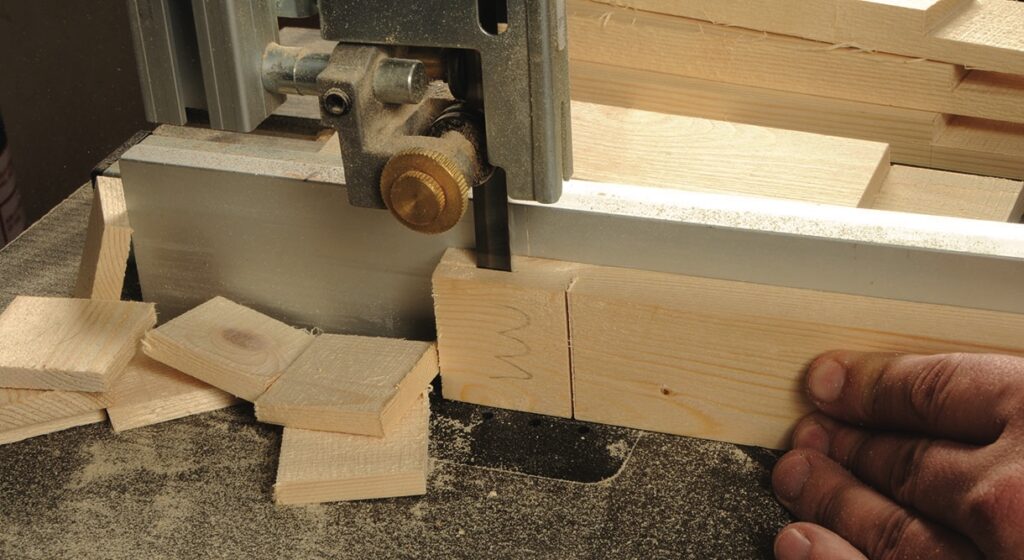 Band saw cutting wooden planks in workshop.