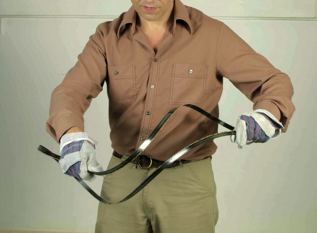 Person holding a metal blade wearing gloves.