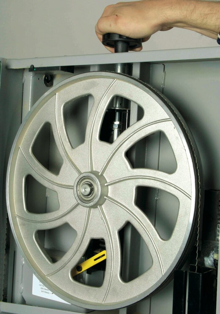 Hand adjusting bandsaw wheel tension mechanism.