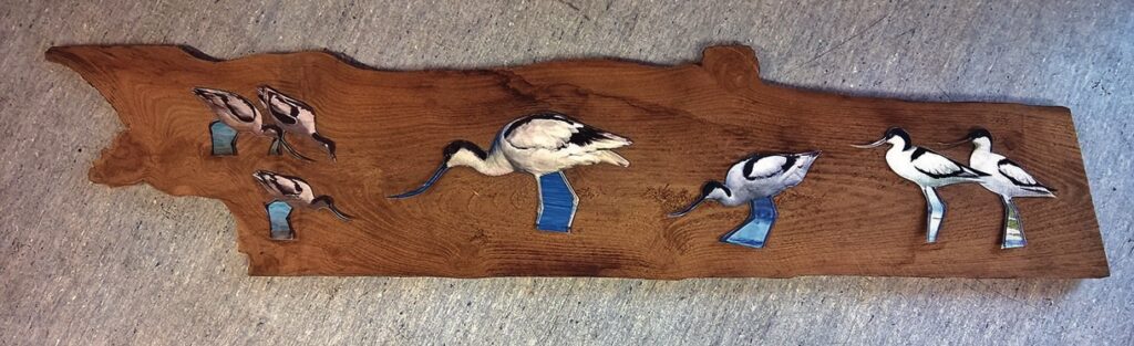 Wooden art panel with bird illustrations.