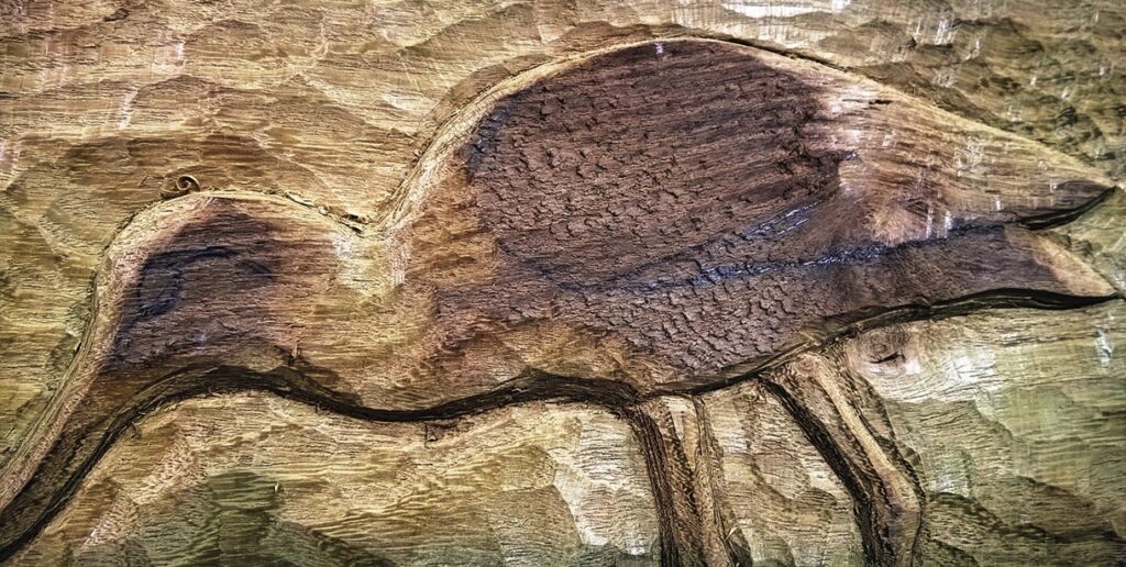 Wooden carving of a bird on textured surface.