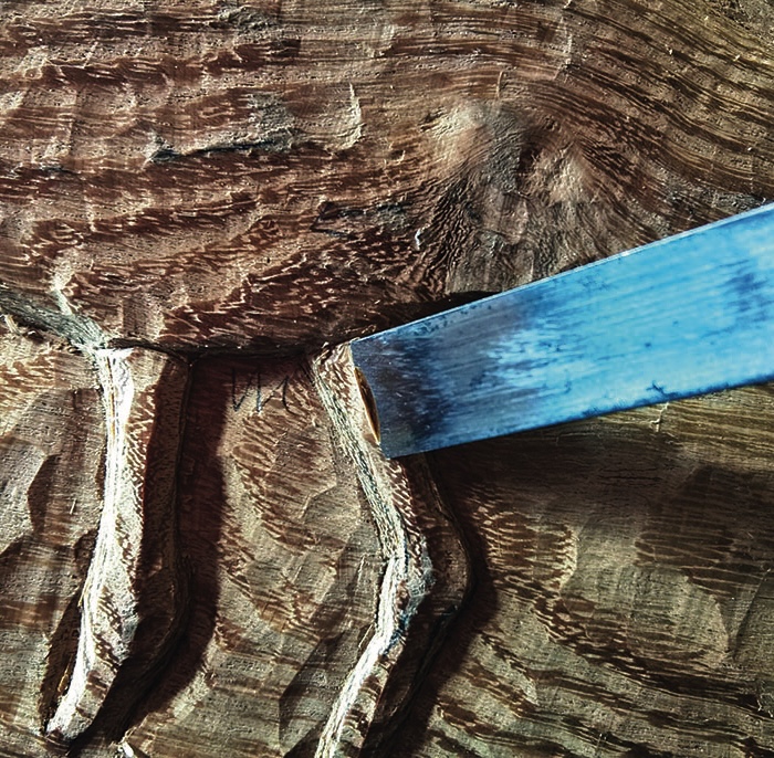 Chisel carving wood with intricate patterns.