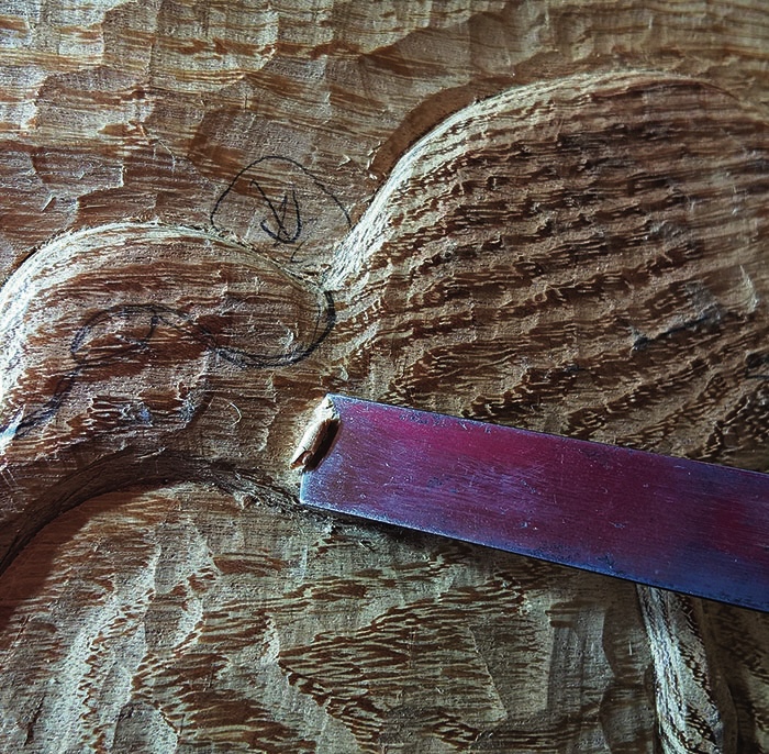 Wood carving in progress with tool.