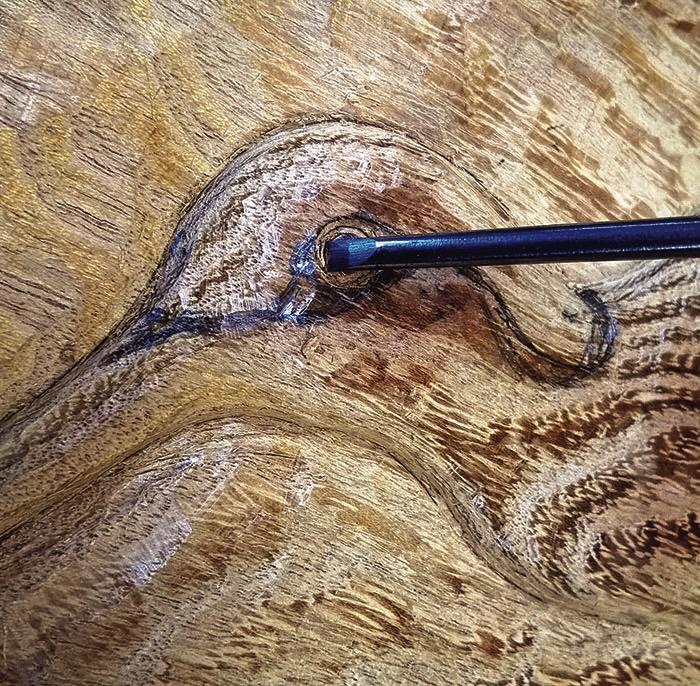 Chisel carving wood detail with intricate grain pattern.