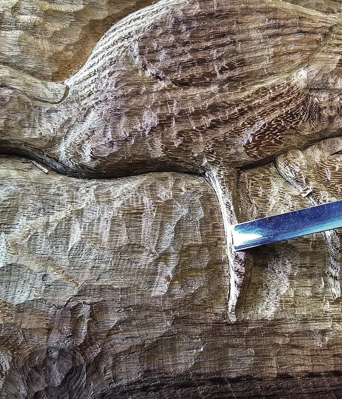 Wood carving in progress with chisel.