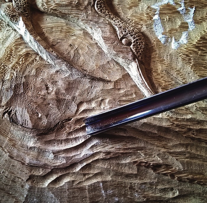 Engraved wood with carving tool close-up.