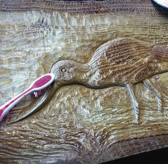 Wooden bird carving cleaned with a toothbrush.