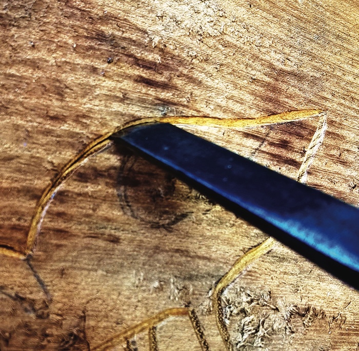 Close-up of carving tool on wooden surface.