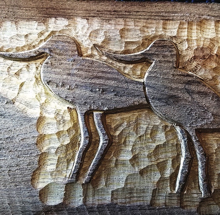 Wood carving of two animals in rustic style.