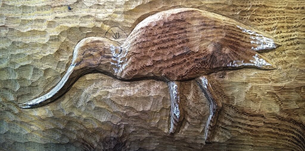 Wooden carving of a bird with long beak.