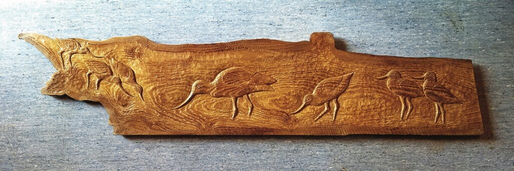 Wooden carving of birds on a branch.