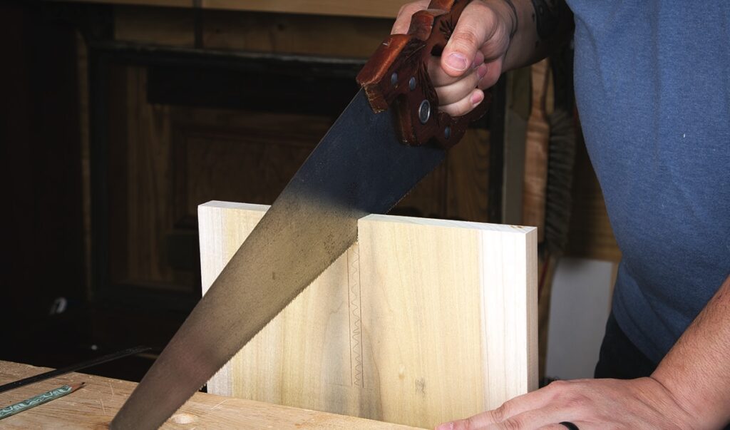 Person sawing wood in a workshop.