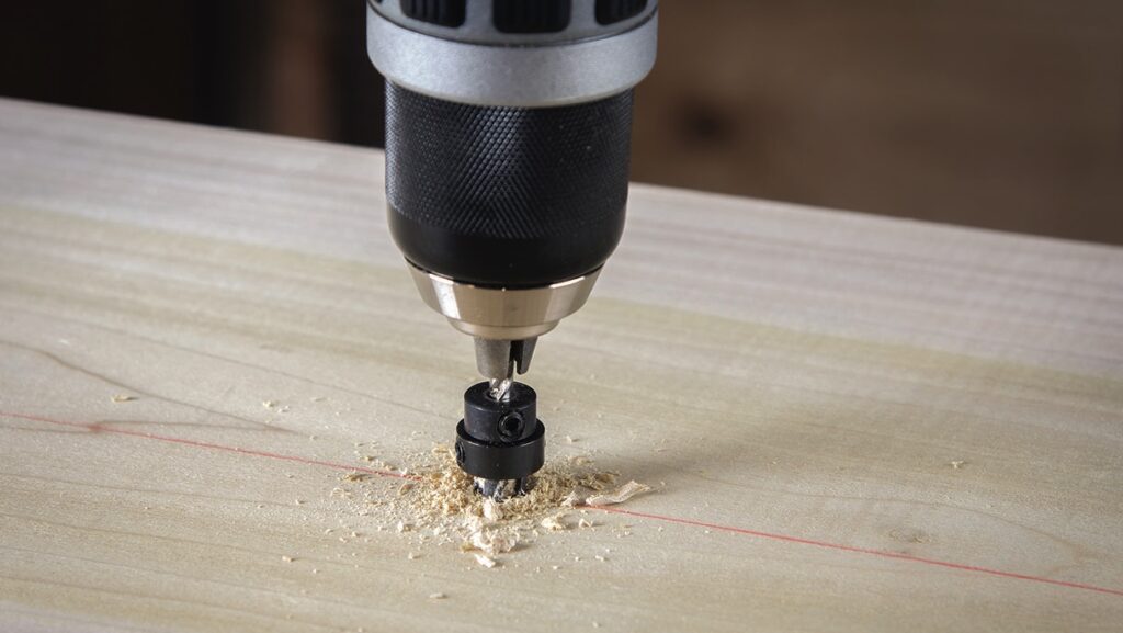 Drill creating hole in wooden surface.