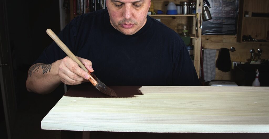 Man painting wooden furniture in workshop
