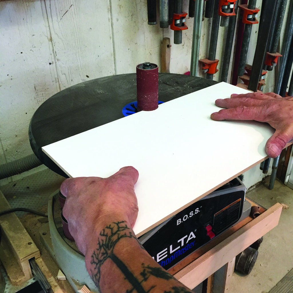 Man sanding wood on a Delta Shopmaster tool.