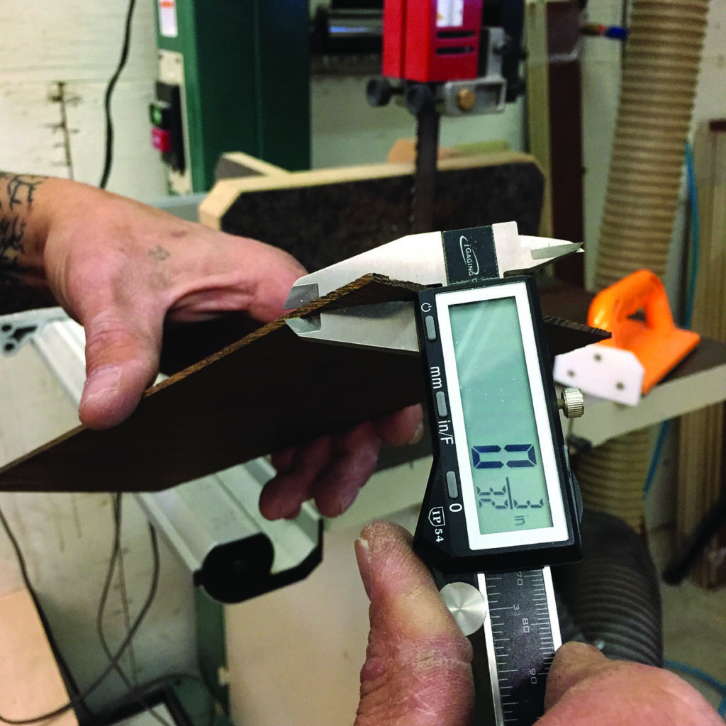 Measuring wood thickness with digital caliper in workshop.