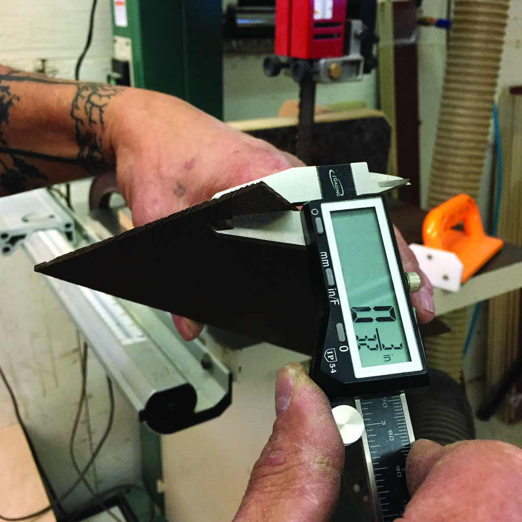 Person measuring wood thickness with digital caliper