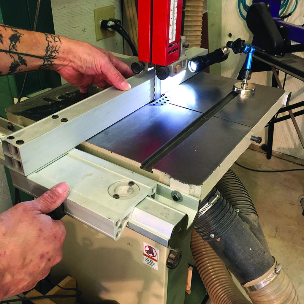 Person adjusting bandsaw guide for precise cutting.
