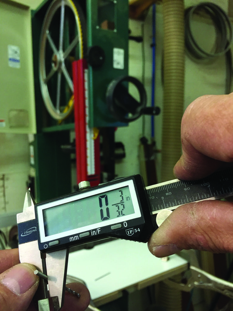Digital caliper measuring small metal object in workshop.