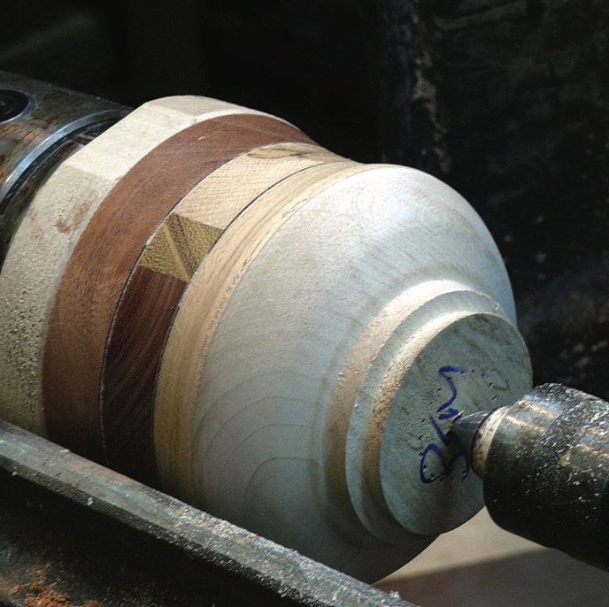 Woodturning on a lathe, close-up of wooden vase.