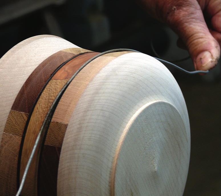 Craftsman shaping wooden bowl with hand tool.