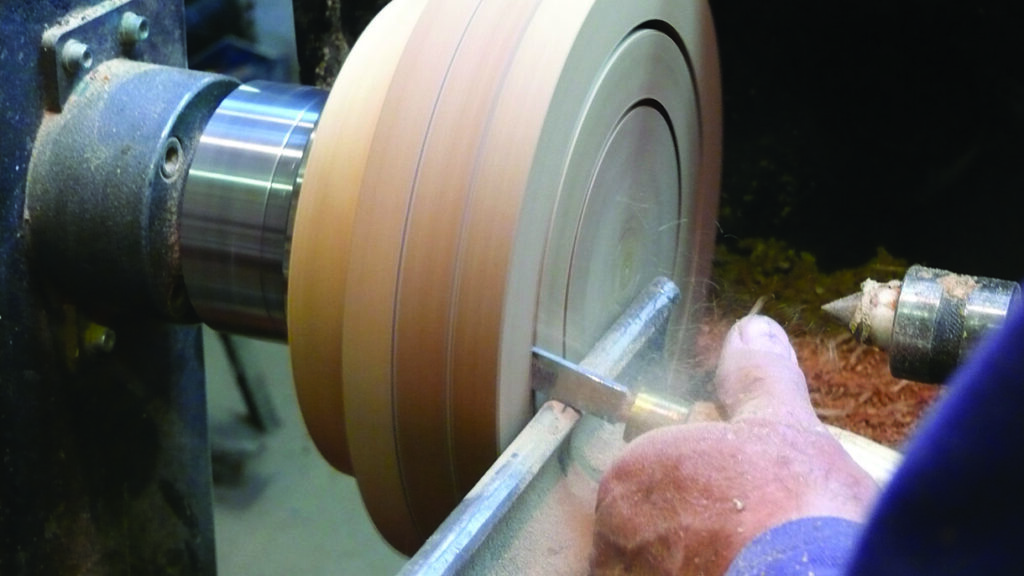 Craftsman using lathe to shape wooden object
