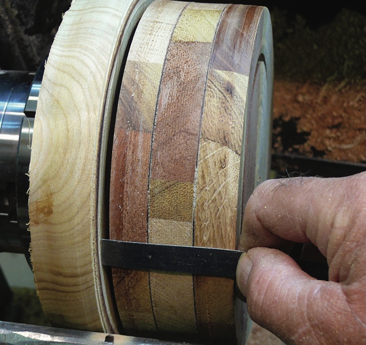 Measuring wooden bowl on lathe with calliper.