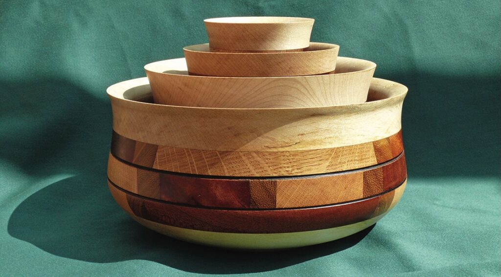 Stacked wooden bowls on green fabric background.