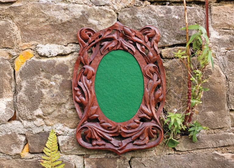 Ornate wooden frame on stone wall with plants